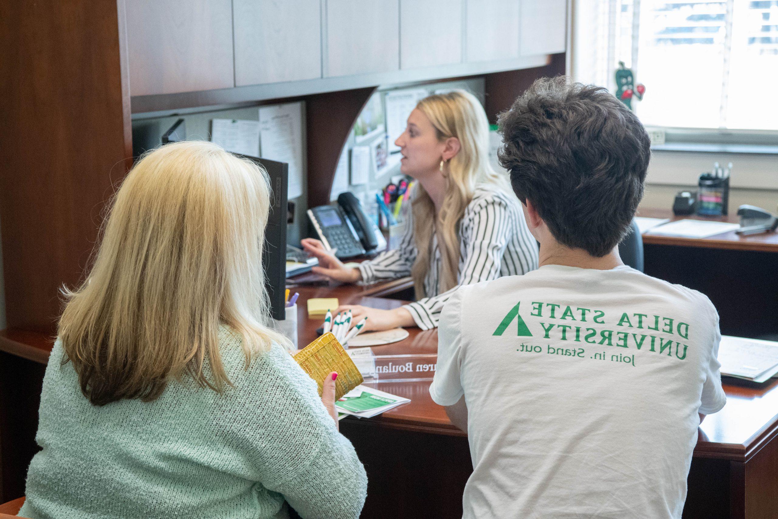 Student with parent talking to financial aid counselor.